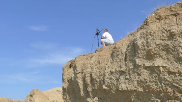 Videógrafo atira na costa em uma câmera montada em um tripé — Vídeo de Stock