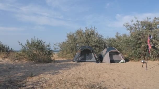 Tourist camp, tents and a car are in the tourist parking lot. On the tripod of the photographer hanging swimsuit moving gusts of wind — Stock Video