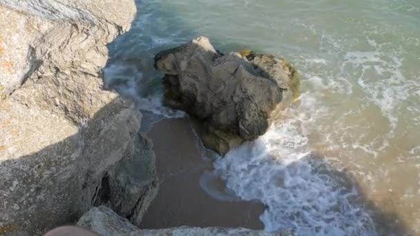 砂浜の海岸を波が洗ってください。岩の上の尾根が壊れています。 — ストック動画