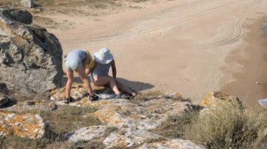 Çocukların uçurumun kenarında oturmak. Dalgalar kumlu kıyı yıkayın. Ridge buzlu kırık