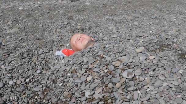 Dítě je posetý kameny. Malý muž pod kameny. — Stock video