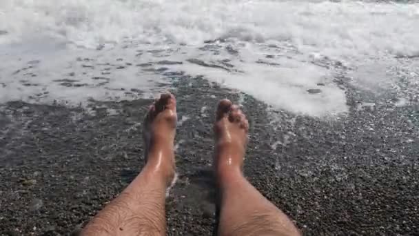 Mens hairy legs in sea surf. Parallel lying bare legs. — Stock Video