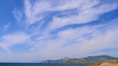 Mavi gökyüzü ile beyaz bulutlar dağlar. Cirrus bulutlar mavi gökyüzünde çalıştırın. En iyi görüş sahil. Güzel manzara deniz. Dağlık kıyılarının en iyi video. İçinde hareket