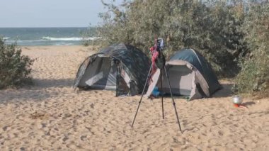 Turist kamp, çadır ve bir araba Turizm Park yerinde vardır. Rüzgarlar fotoğrafçı asılı mayo tripod üzerinde hareket.