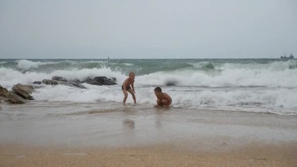 Il bambino gioca sulla spiaggia. ragazzo nella sabbia che mangia anguria. Il bambino tiene in mano una crosta verde di cultura del melone . — Video Stock