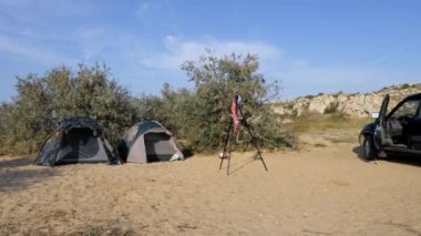 Turist kamp, çadır ve bir araba Turizm Park yerinde vardır. Rüzgarlar fotoğrafçı asılı mayo tripod üzerinde hareket