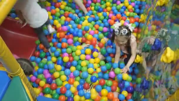 Ruang bermain Childrens. Anak-anak bermain di sebuah baskom kering penuh dengan bola berwarna plastik . — Stok Video