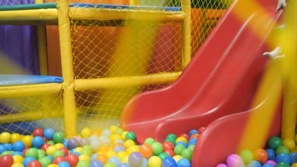 Sala de juegos para niños. Los niños juegan en un lavabo seco lleno de bolas de plástico de color . — Vídeos de Stock