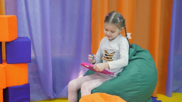 Childrens speelkamer. Schattig klein meisje verven op een Magnetisch Krijtbord speciale pen. — Stockvideo