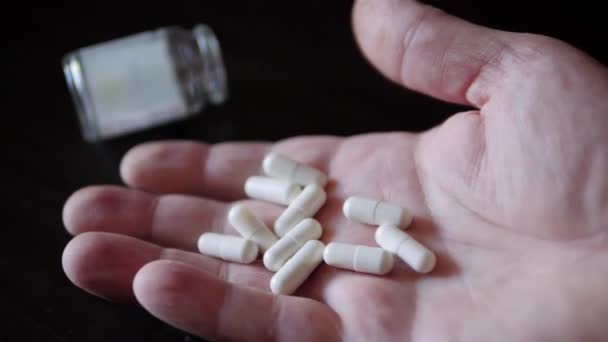 薬物中毒 薬瓶から丸薬ビタミン剤や薬の錠剤を手に示します — ストック動画