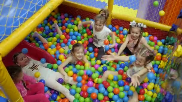 Kinderspielzimmer. Kinder spielen in einem Trockenbecken, das mit farbigen Plastikbällen gefüllt ist. — Stockvideo