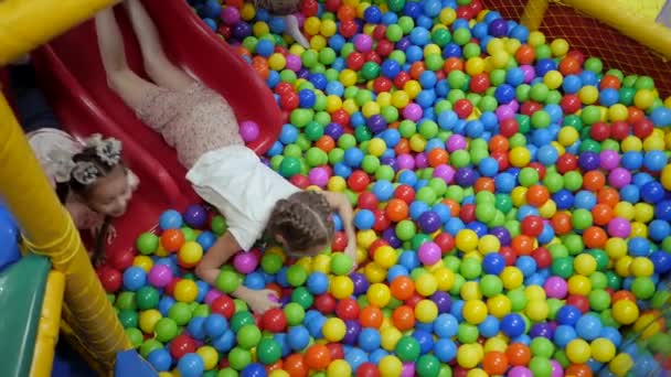 Játszószoba gyerekeknek. Gyerekek játszanak a száraz medencében tele műanyag színű golyókat. — Stock videók