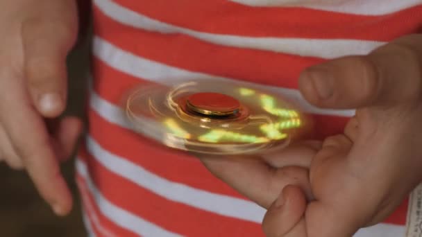 Jouet filant, fileur, dans les mains d'un garçon aux cheveux blonds .