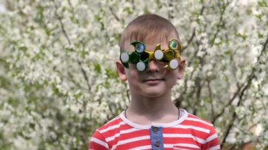 Bardaktaki spinner dönüyor. Sokakta eğlenceli. Komik bir yüzünde dönen bir oyuncak. Kiraz ağacının çiçek açan beyaz çiçekleri arka planda bir çocuk.