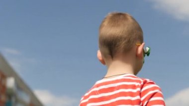 Bardaktaki spinner dönüyor. Sokakta eğlenceli. Mavi gökyüzüne karşı bebek çocuk.