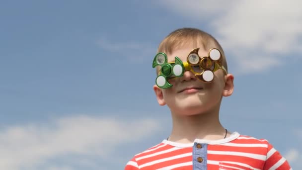 Spinner on the glasses is spinning. Fun on the street. Baby boy against the blue sky. — Stock Video