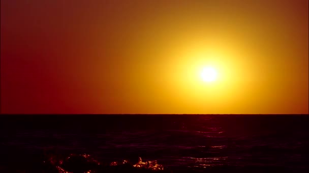O sol vermelho põe-se sobre o horizonte no oceano. Um corpo celestial afunda no mar . — Vídeo de Stock