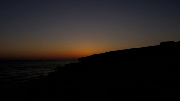 Amanecer en la playa. El sol sale de detrás de las montañas . — Vídeos de Stock