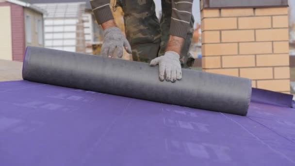 Installation of the roof base. Flooring substrate under the roof. Laying of a roofing carpet. The rolling of the insulation material in the oriented strand Board stove. — Stock Footage Installation Roof Base Flooring Substrate Roof Laying Roofing Carpet Rolling Stock Video