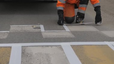 Yol işaretleri. Otobanda yaya yaya geçidini işaret ediyor. Boya kalıbı uyguluyorum. Asfaltta maskeleme bandı. Yolun gelecekteki çiziminin doğru çizgilerini işaretliyor.