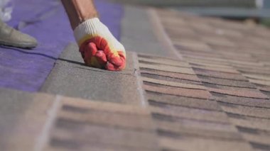 Çatı işi. Özel bir evin çatısına yumuşak bir çatı sermek. Esnek çatı malzemeleriyle çalışıyor. Çatıyı çivi ve çekiçle tamir etmek. Yumuşak döşeme tablosunun hizalanması.