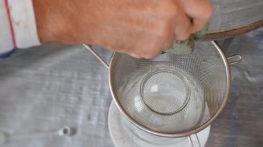 Arıcı, bal sökücünün sapını çevirir ve bir bal akıntısı oluşturur. Arı yetiştiricisi arılara bal pompalıyor. Çevre dostu bir ürün. Bal peteğinden bal çıkarıyorum. Depodaki sıvıyı boşaltıyorum. Filtreleme Dizinleri