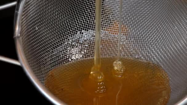 Biodlaren vrider på honungsextraktorns handtag och en ström av honung rinner. Biodlaren pumpar honung på bigården, en miljövänlig produkt. — Stockvideo