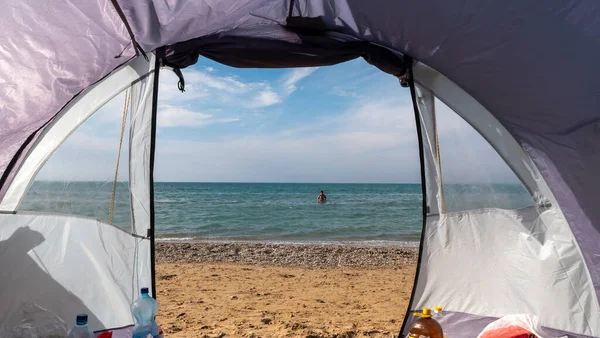 View through the open entrance to the tent on the sea. Sandy beach. Camping on the beach. Vacation on the black sea coast. Sandy village, Bakhchisaray district, Republic of Crimea, centre Peschanokopskogo rural settlement.