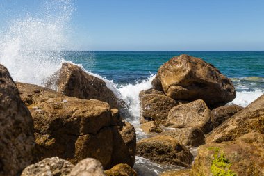 Güneşli bir günde kayalara vuran bir dalganın sıçramaları..