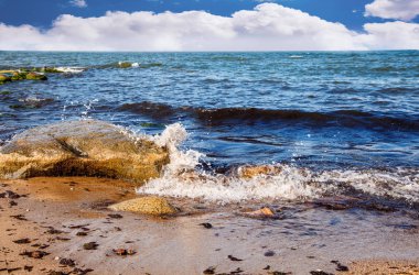 dalgalar deniz büyük bir taş üzerinde bulutlu yaz gününde yıkmak