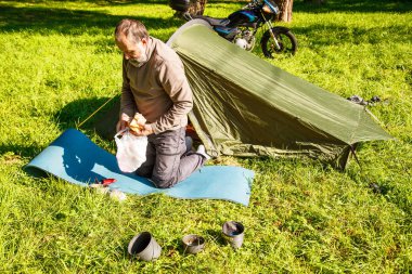 Yaşlı Turizm güneşli yaz gününde yakınındaki ormanda çadırını kahvaltı hazırlarken
