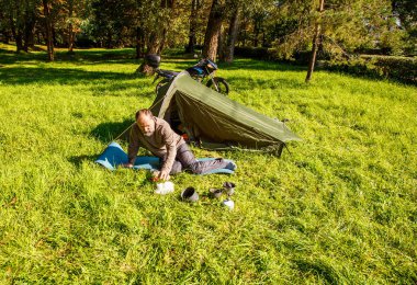 Yaşlı turist yakınındaki ormanda çadırını güneşli yaz gün oturup istirahat
