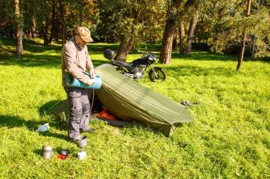 Yaşlı turist foldjng güneşli yaz gününde ormandaki bir çadır