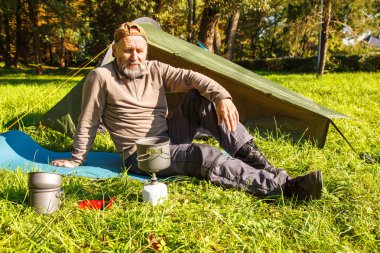 Yaşlı turistik bir çay güneşli yaz gün closeup orman çadırında yakınındaki taşınabilir bir ocakta kaynayan