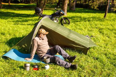 Yaşlı turist yakınındaki ormanda çadırını güneşli yaz gün oturup istirahat