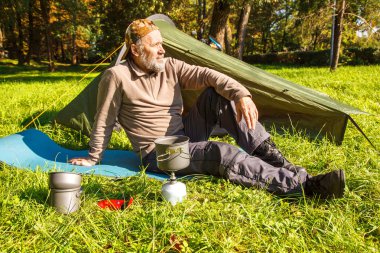 Yaşlı turistik bir çay yakınındaki ormanda çadırını üzerinde güneşli yaz günü soba bir Portable kaynar