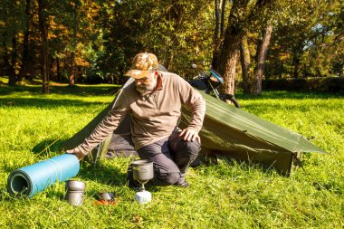 Yaşlı turist foldjng güneşli yaz gününde ormandaki bir çadır