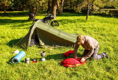 Yaşlı turist foldjng güneşli yaz gününde ormandaki bir çadır