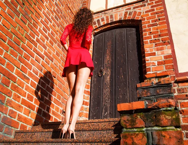Kırmızı elbiseli Genç kadın güneşli yaz gününde merdivenlerde arkası duruyor
