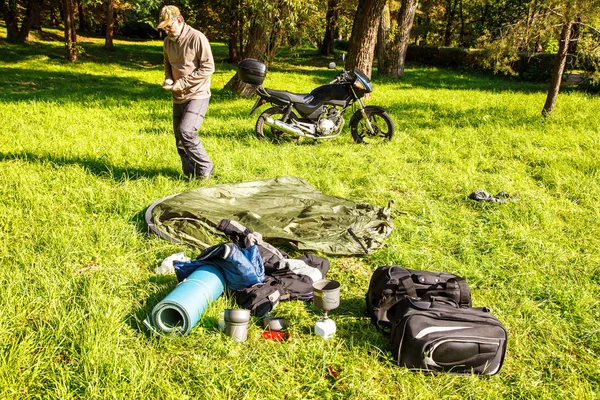 Yaşlı turist foldjng güneşli yaz gününde ormandaki bir çadır