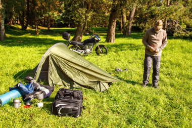 Yaşlı turist foldjng güneşli yaz gününde ormandaki bir çadır