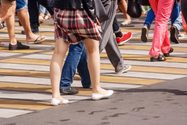 Güneşli bir yaz gününde şehrin işlek caddesinde yaya geçidini geçen bir sürü insan var.