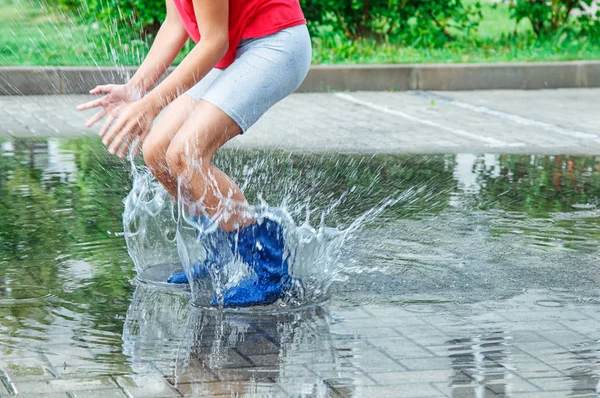 ゴムの女の子は 夏の日の屋外の雨の後水たまりにジャンプ ブーツします 足のクローズ アップ — ストック写真