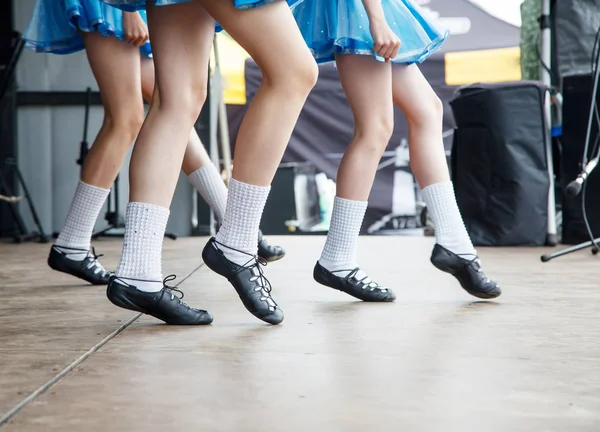 female legs of three irish dancers in blue dresses on the stage closeup