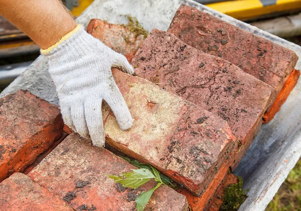 worker puing the brick in the wheelbarrow outdoor. hand closeup