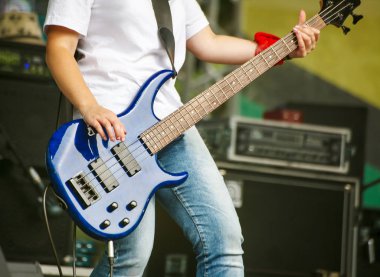 Sahne Alanı'ndaki bir rock konserinde kadın gitarist. Eller yukarı