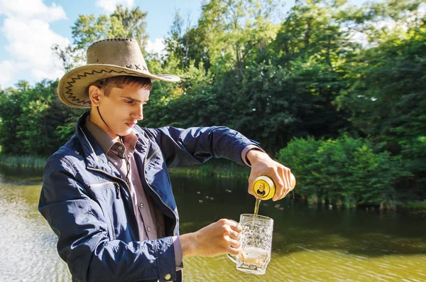 Junger Mann schüttet Bier aus einem Glas in einen Becher — Stockfoto