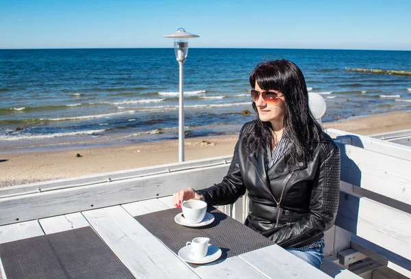 Jovem morena bebendo café em um café ao ar livre perto do — Fotografia de Stock