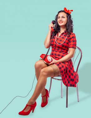 gülümseyen genç pinup kadın bir sandalyede oturan ve telefon konuşurken