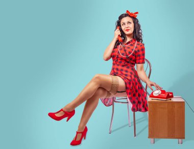 mutlu genç pinup kadın bir sandalyede oturan ve telefonda konuşurken